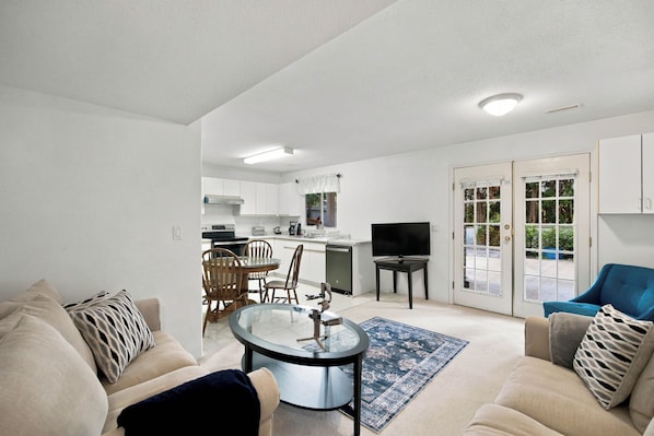 A modern living room with a glass-top coffee table, beige sofas, and a blue rug.