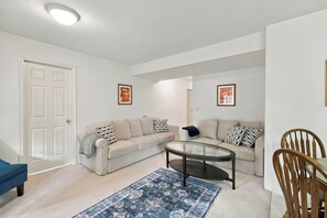 Ein Wohnzimmer mit zwei Sofas, einem Couchtisch, einem blauen Teppich und einem Holzstuhl.