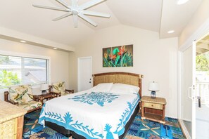 A bedroom with a bed, a ceiling fan, a painting, a window with blinds, and a chair. - Extended Escape! Waimanalo Beach Cottages, Unit 11 (Waimanalo)