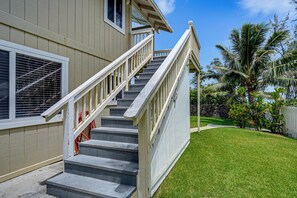 Ein Wohnhaus mit einer Treppe, die zum Eingang führt, einem gepflegten Rasen und einer Steinmauer im Hintergrund.