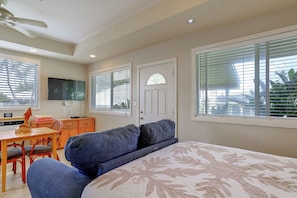 A bedroom with a bed, a desk, a chair, and a television. - Waimanalo Beach Cottages - Large Studio, Unit 4 (Waimanalo)