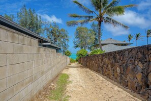 En smal sti omkranset af stenvægge, der fører hen til en bygning med et skråt tag.