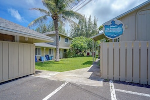 Ein Wohngebiet mit einem Schild für die Waimanalo Beach Cottages, einer gepflasterten Einfahrt und einer Palme.