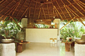 Zona de recepción con techo de paja y un letrero que dice 'Khubani Beach Resort Goa'.