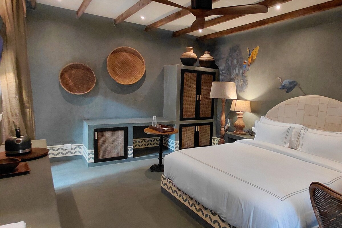 Habitación de hotel con una cama, una mesa y una silla. Decoración en las paredes y una lámpara.