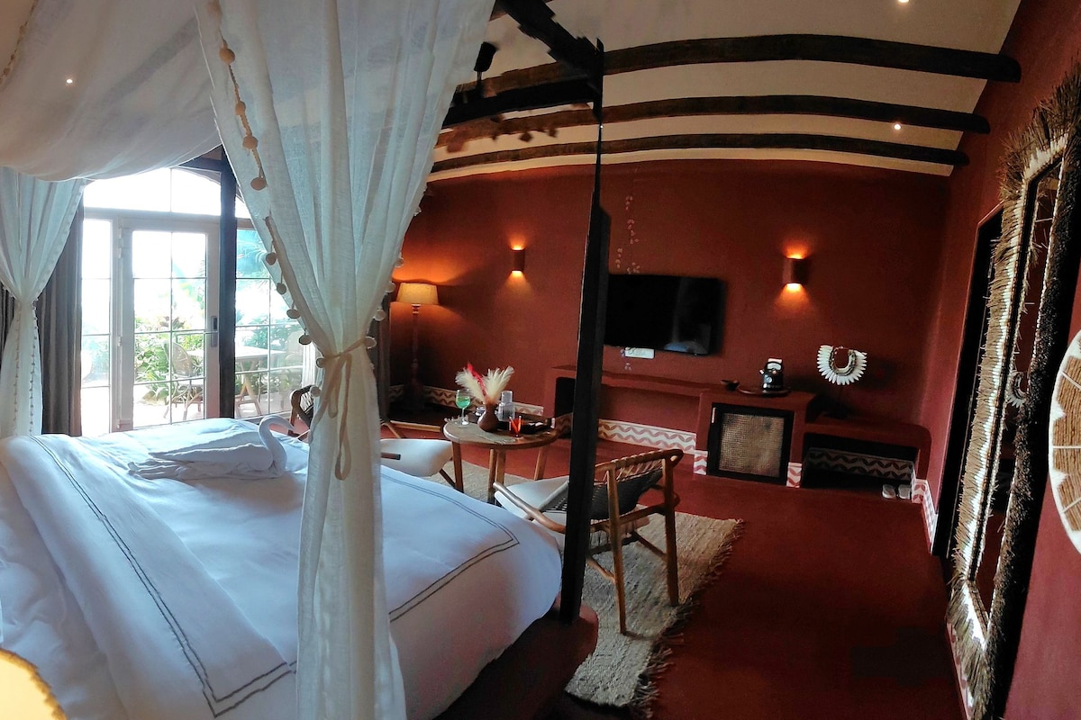 Una habitación de hotel con una cama, un televisor, una mesita con una lámpara y un adorno en la pared.