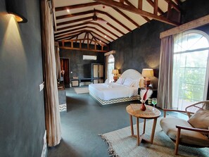 Un dormitorio con una cama grande, una zona de estar con una silla y vistas al exterior.