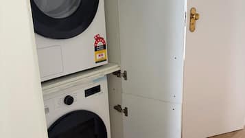 A compact, white laundry room with two front-loading washing machines and a door with a brass handle.