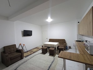 Ein modernes Wohnzimmer mit einer Couch, einem Couchtisch und einem an der Wand befestigten Fernseher.