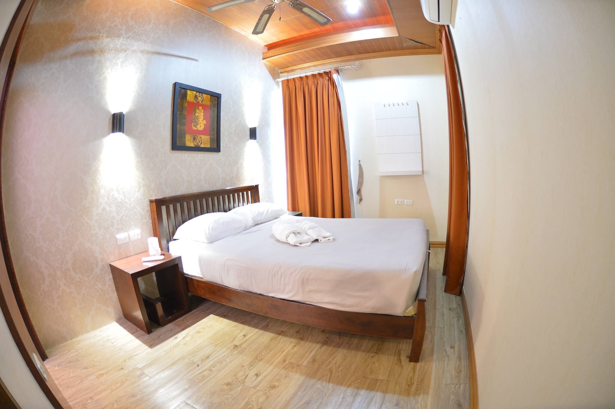 A bedroom with a wooden bed, a nightstand, a ceiling fan, and a wall-mounted air conditioner.