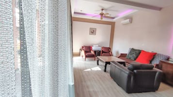 A living room with a sofa, armchairs, a coffee table, and a dining area with chairs and a table.