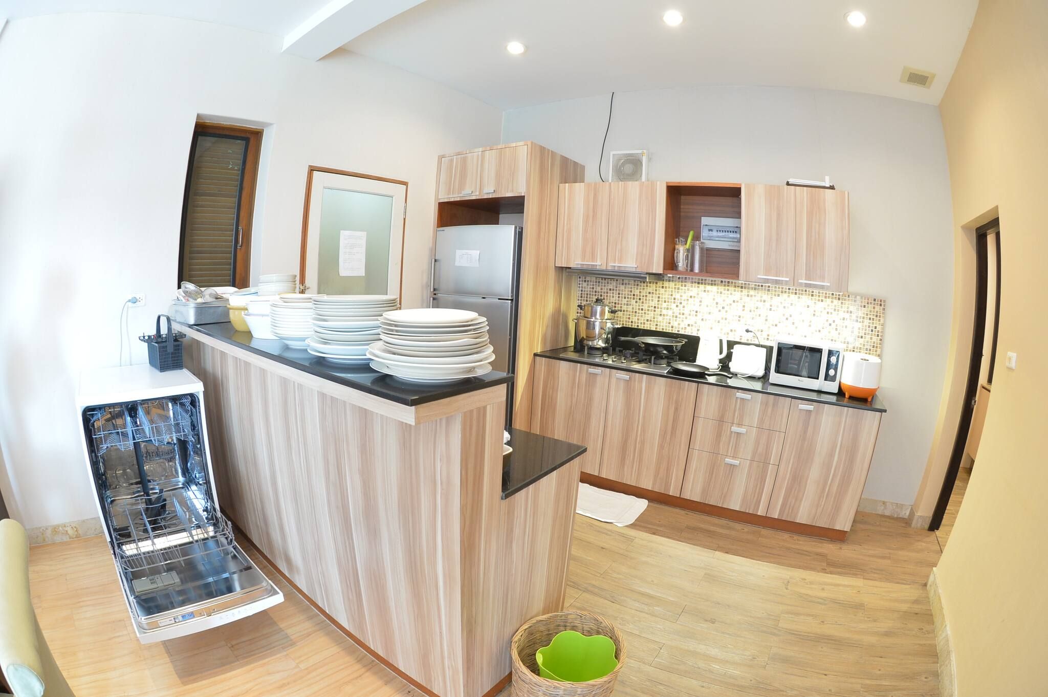A modern kitchen with wooden cabinets, a built-in dishwasher, and a microwave.