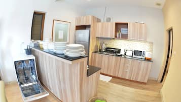 A modern kitchen with wooden cabinets, a built-in dishwasher, and a microwave.