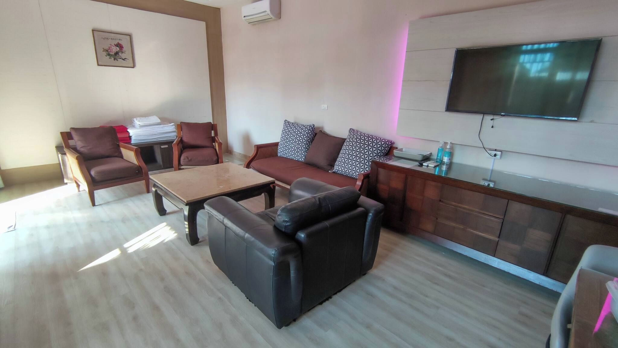 A living room with a sofa, armchairs, a coffee table, and a flat-screen TV mounted on the wall.