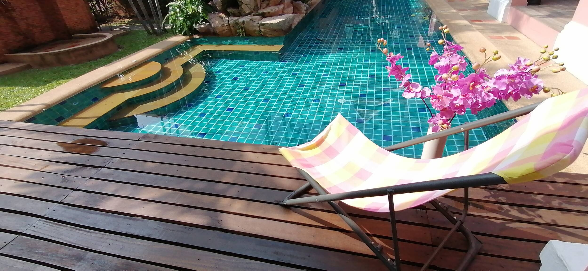 Piscina com borda azulejada e deck de madeira.
