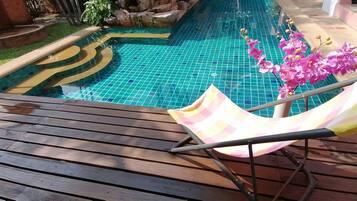 Piscina com borda azulejada e deck de madeira.