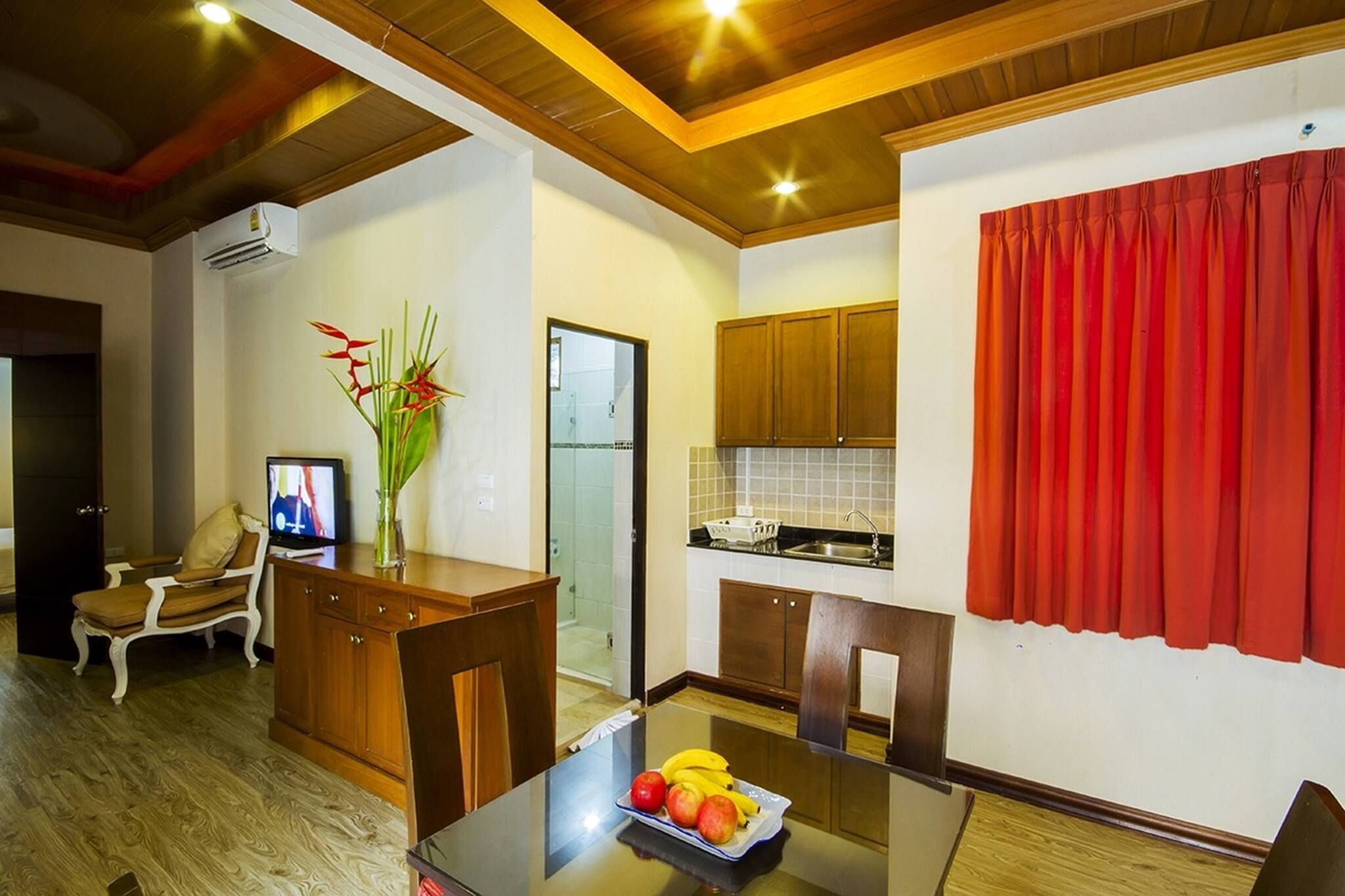 A compact living space with a dining area, kitchenette, and a seating area with a television.