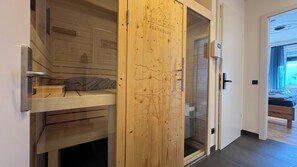 Eine Holztür mit Skimotiv, eine Bank und ein kleiner Tisch mit einem Handtuch.
