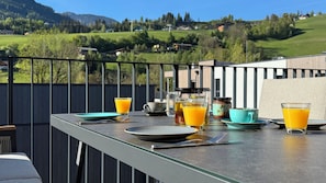 A breakfast table with a view of a green landscape and mountains in the background. - AlpinHerz Luxury Penthouse with Private Sauna | 2 min. to the slopes | E-Wallbox (Schladming)