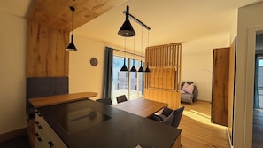 Eine moderne Küche mit Kochinsel, Pendelleuchten und Blick auf einen Balkon.