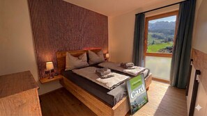Ein Schlafzimmer mit einem hölzernen Bett, einem Nachttisch, einer Lampe und Bergblick durch ein Fenster.