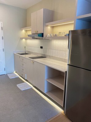 A modern kitchen with a stainless steel refrigerator, a double sink, and light wood cabinetry. - Apartment in Pattaya (Pattaya City)
