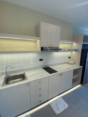 A modern kitchen with a stainless steel sink, light-colored cabinetry, and a built-in stove. - Apartment in Pattaya (Pattaya City)