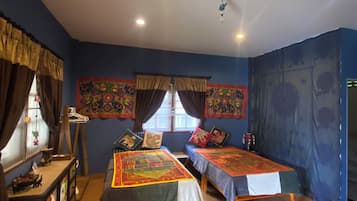 A room with two beds, a desk, and a window with curtains.