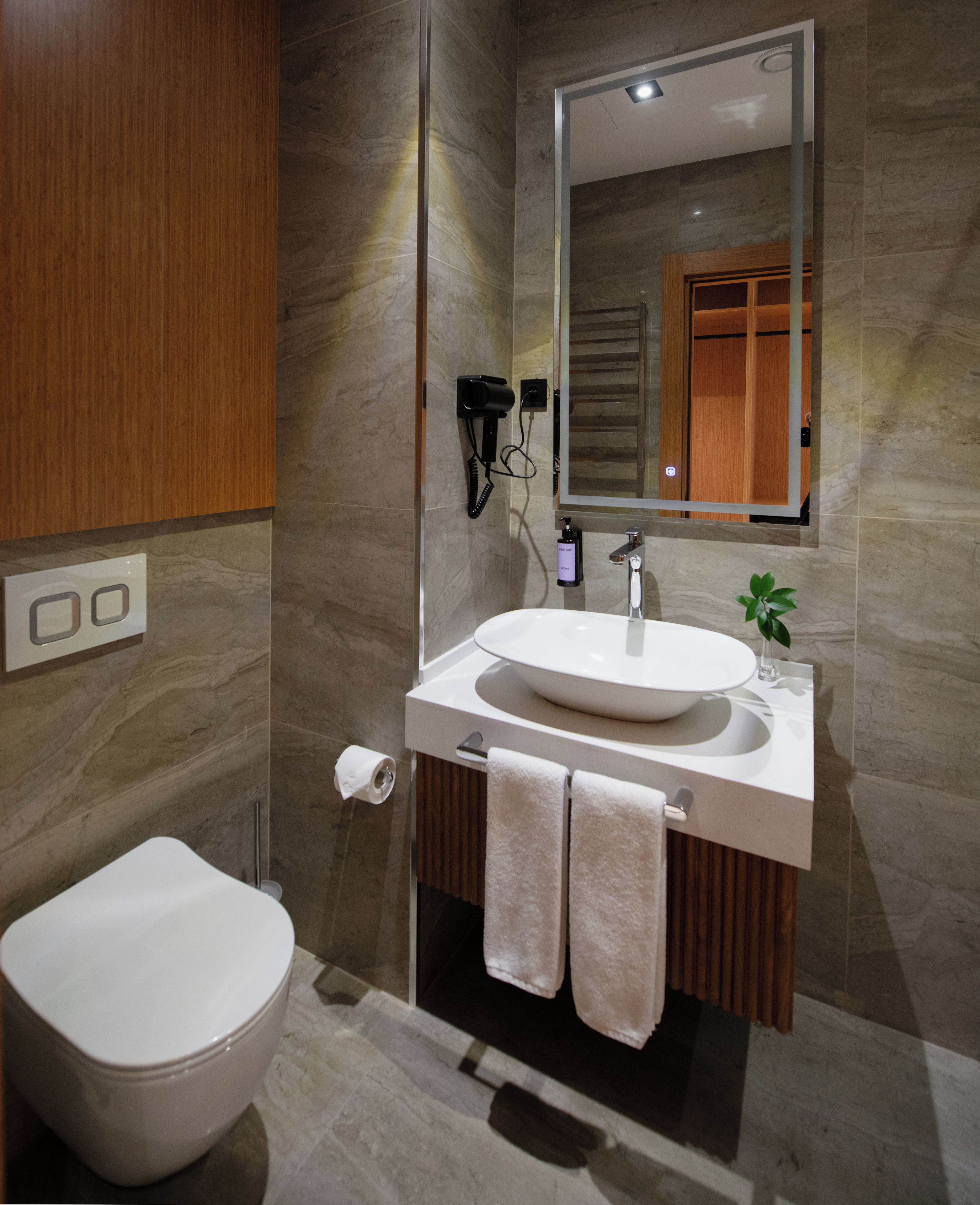 A modern bathroom with a white sink, mirror, and toilet.