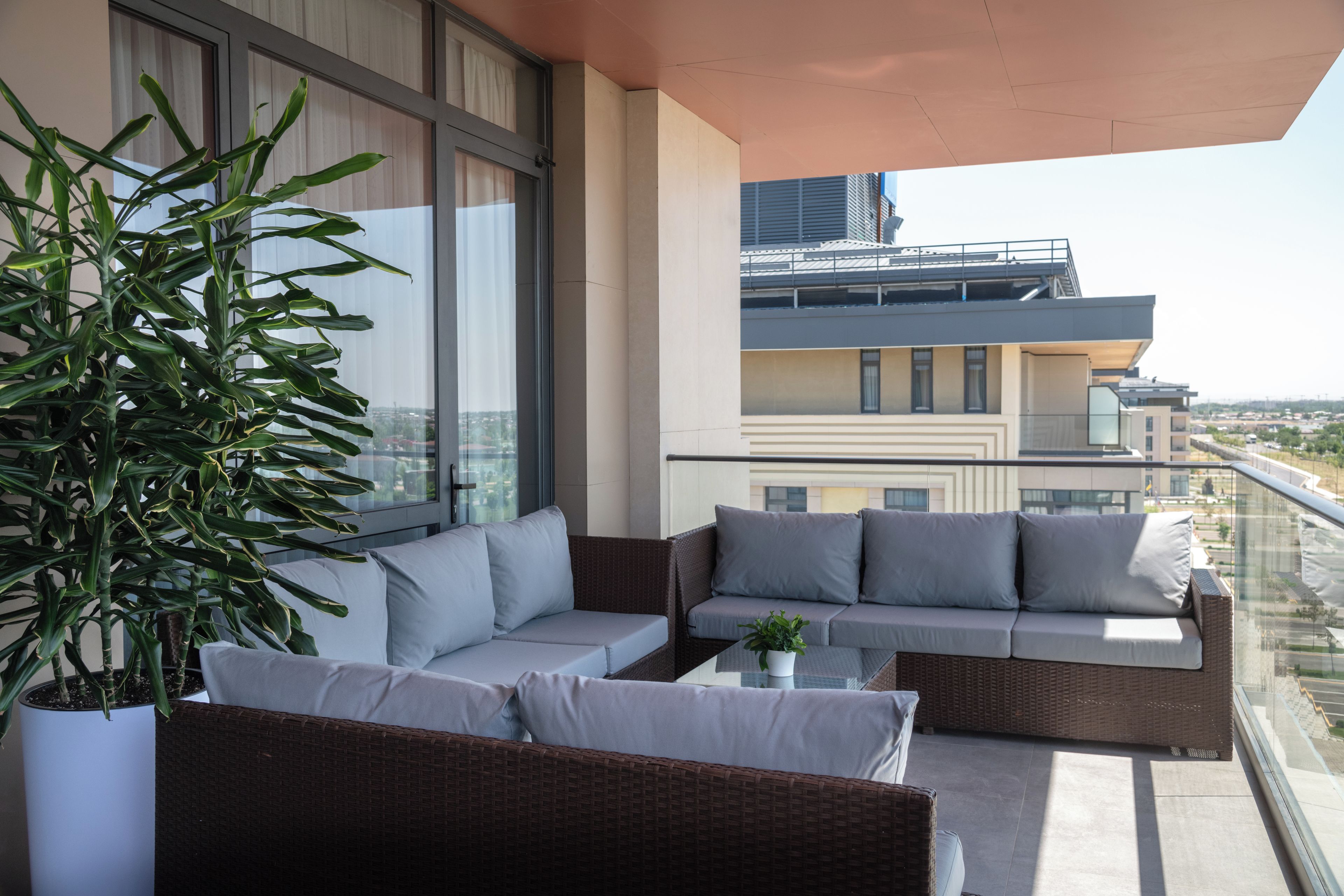 A balcony with a sofa, a potted plant, and a view of the cityscape.