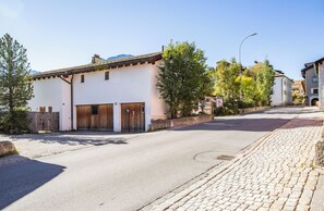 A quiet street with traditional buildings, a cobblestone sidewalk, and a clear sky. - The Green Hut – Sunny Family Apartment Near St. Moritz & the Ski Slopes (Celerina/Schlarigna)