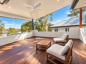 A spacious balcony with wooden flooring, a ceiling fan, and two cushioned chairs. - The Ferricks |2BR Cosy Stafford Home (Stafford)