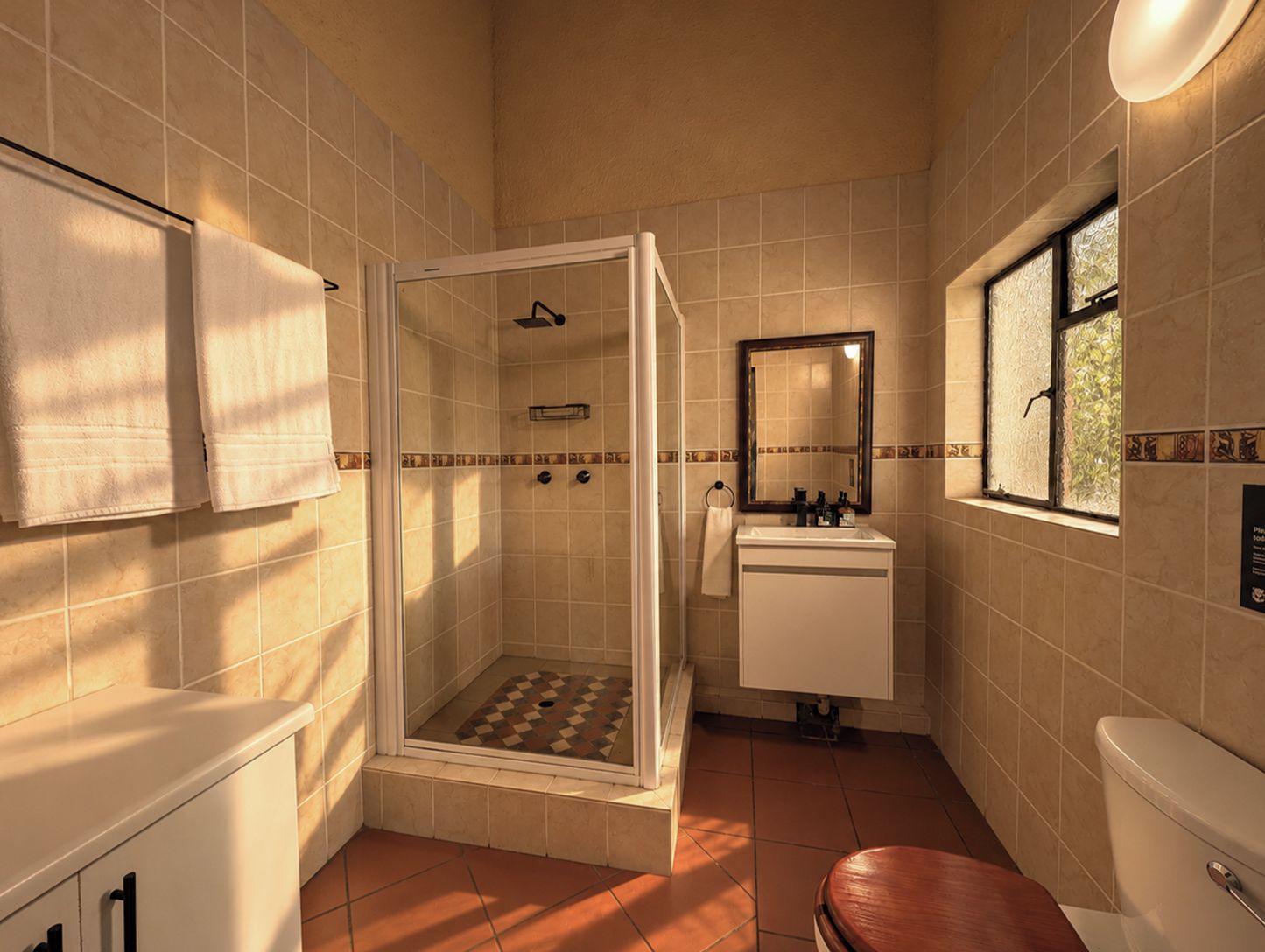 A bathroom with a shower, sink, toilet, and a window.