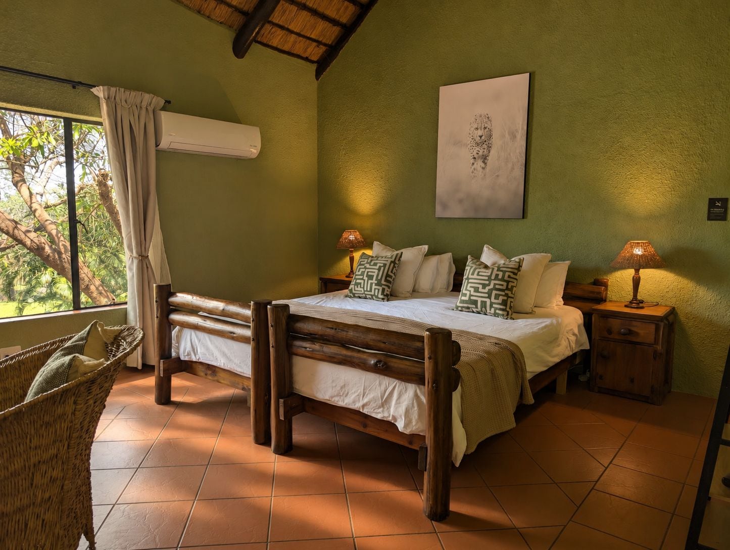 Quarto com cama, cadeira, mesa de cabeceira, luminária e um quadro na parede.