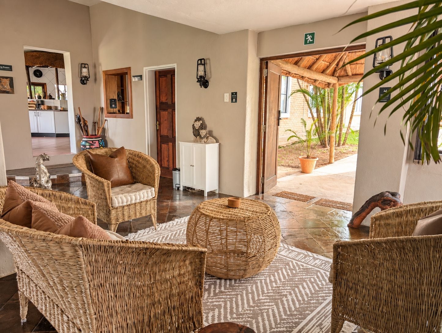 Un hall con muebles de mimbre, un armario blanco y una puerta que da al exterior.