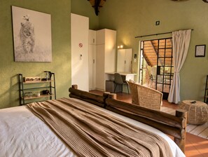 Una habitación con cama, escritorio, silla y ventana con cortinas.