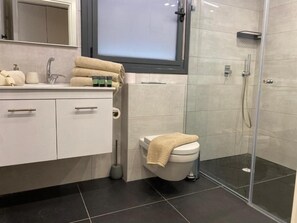 A modern bathroom with a toilet, sink, and shower area. - Biankini Royal suites (Jerusalem)