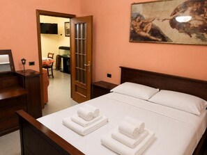 A hotel room with a bed, a desk, a chair, a television, and a painting on the wall. - VACATION HOME in CILENTO, ASCEA - ITALO & SILVIO (Campania)