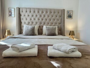 A hotel room with a large bed, two bedside lamps, and a brown carpet. - Belani Bay Apartment 11 | Balcony and Parking in Tivat (Tivat)