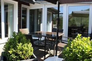 An outdoor patio with a glass table and chairs, surrounded by potted plants. - Holiday home with 2 bedrooms (Winterberg-Niedersfeld)