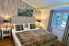 A bedroom with a large bed, two bedside tables, a wall-mounted artwork, and a window with curtains. - Holiday home with 2 bedrooms (Winterberg-Niedersfeld)