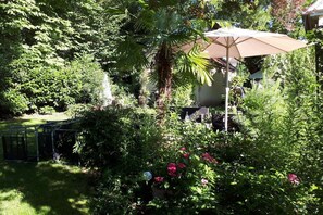 Een weelderige tuin met verschillende planten en een patio met een parasol.