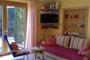 A living room with a sofa, a chair, a television, and a bookshelf. - Holiday apartment with 0 bedrooms (Herxheim)