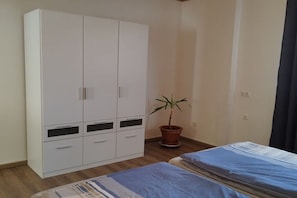 Een slaapkamer met een bed, een kledingkast en een plant in een pot.