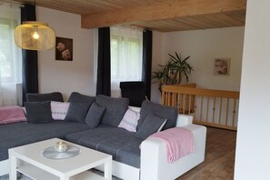 A living room with a grey sofa, white coffee table, and a hanging light fixture. - Holiday apartment with 3 bedrooms (Oberzent Airlenbach)
