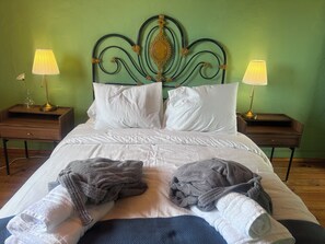 A neatly made bed with white linens and two pillows, flanked by two bedside tables with lamps, against a green wall. - VILLA_mom (CN)