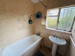 Een badkamer met een bad, een wastafel en een raam.
