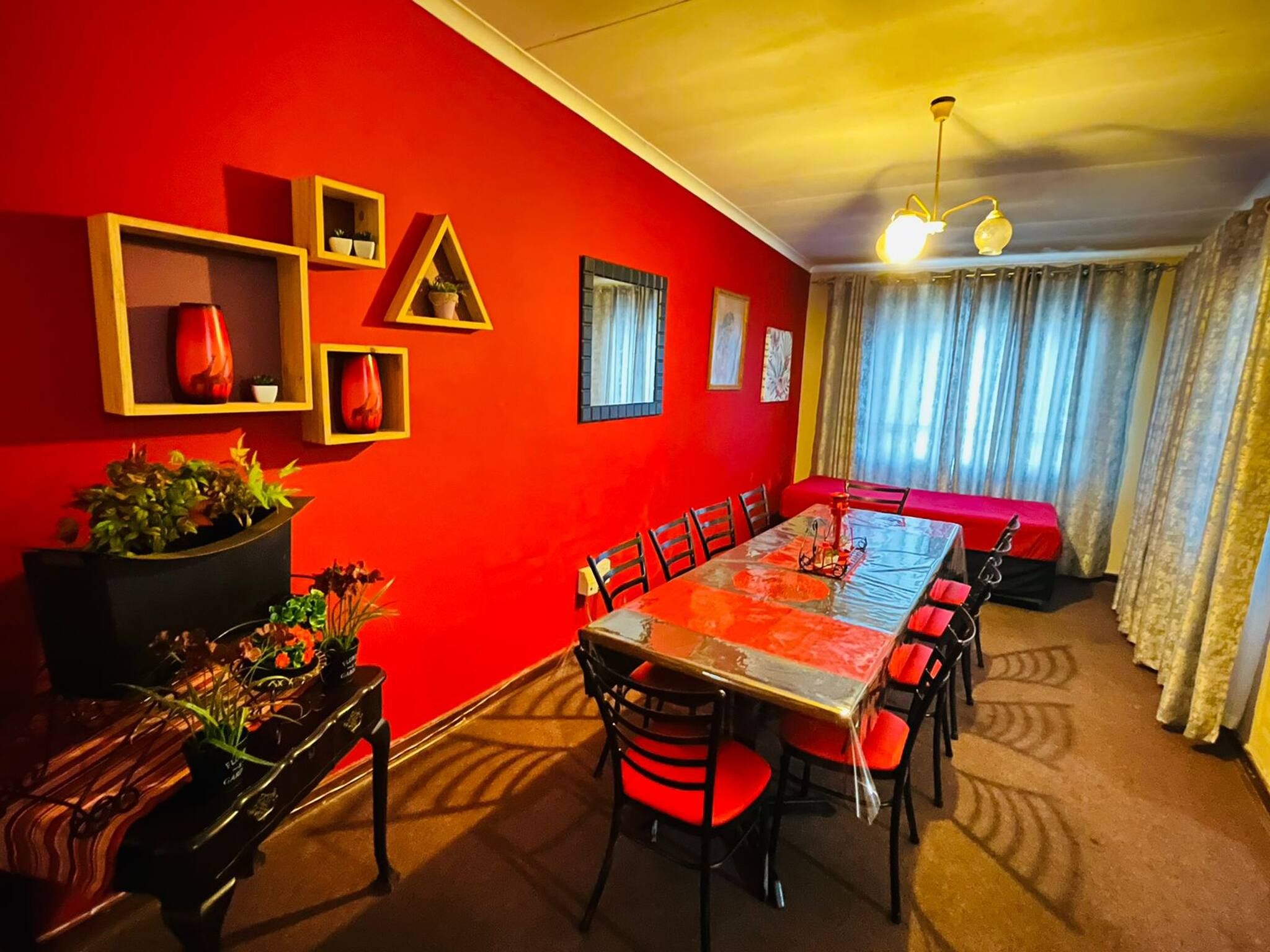 Un área de comedor con pared roja, una mesa con sillas y un sofá.