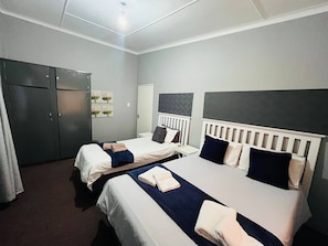 Een hotelkamer met twee bedden, een kledingkast en een radiator.