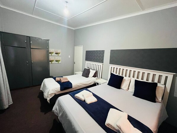 A hotel room with two beds, a wardrobe, and a radiator.